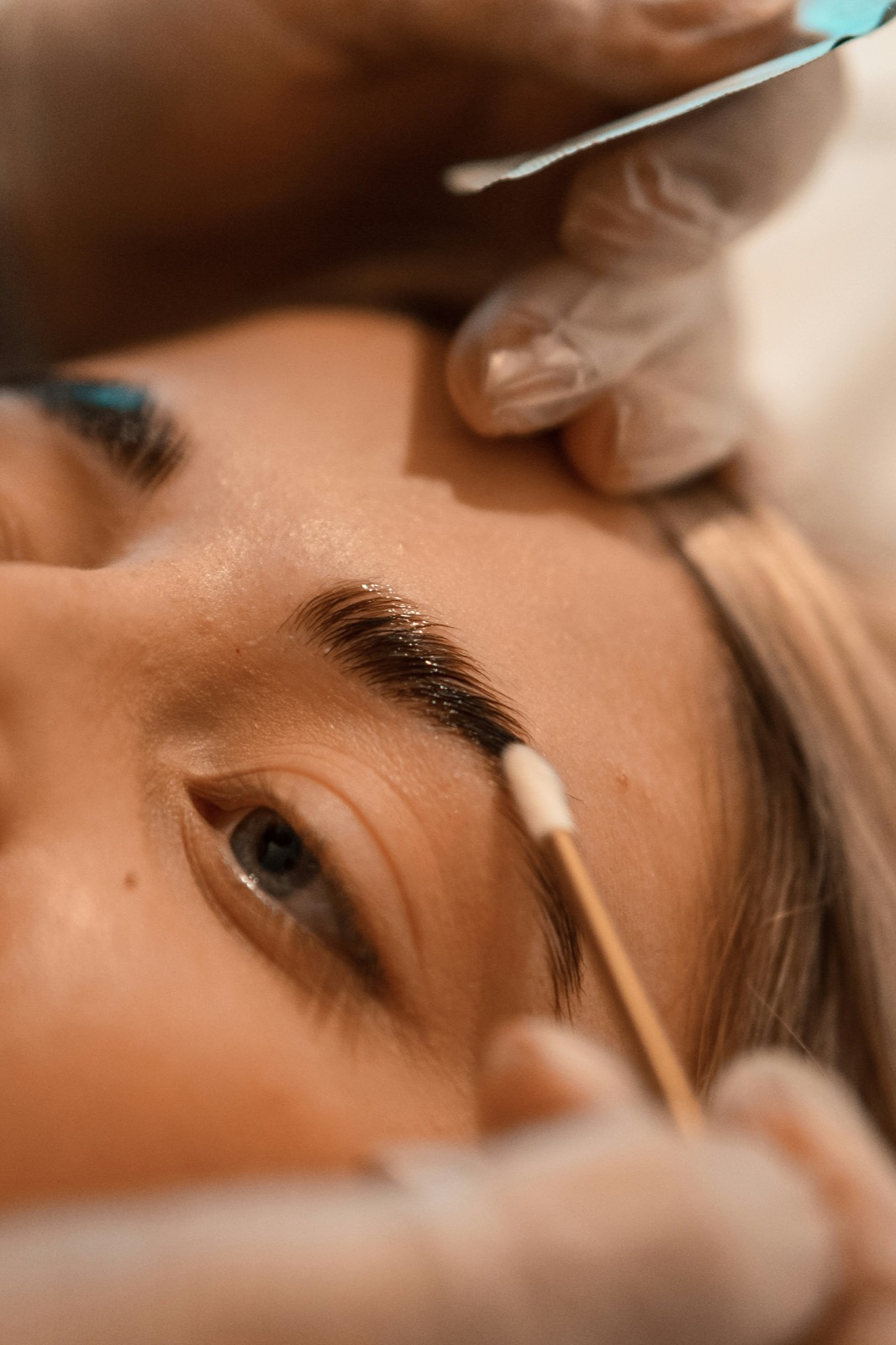 An esthetician applying a brow lamination and tinting treatment