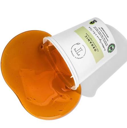 A cup of amber sugar wax paste